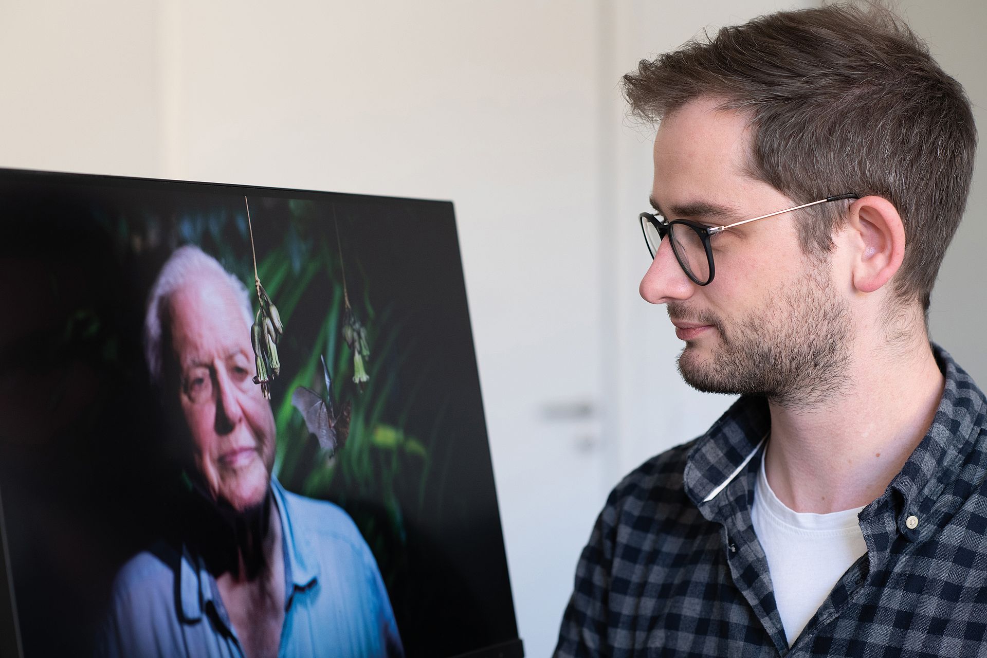 Junger Mann blickt auf Abbildung eines alten Mannes mit Fledermaus