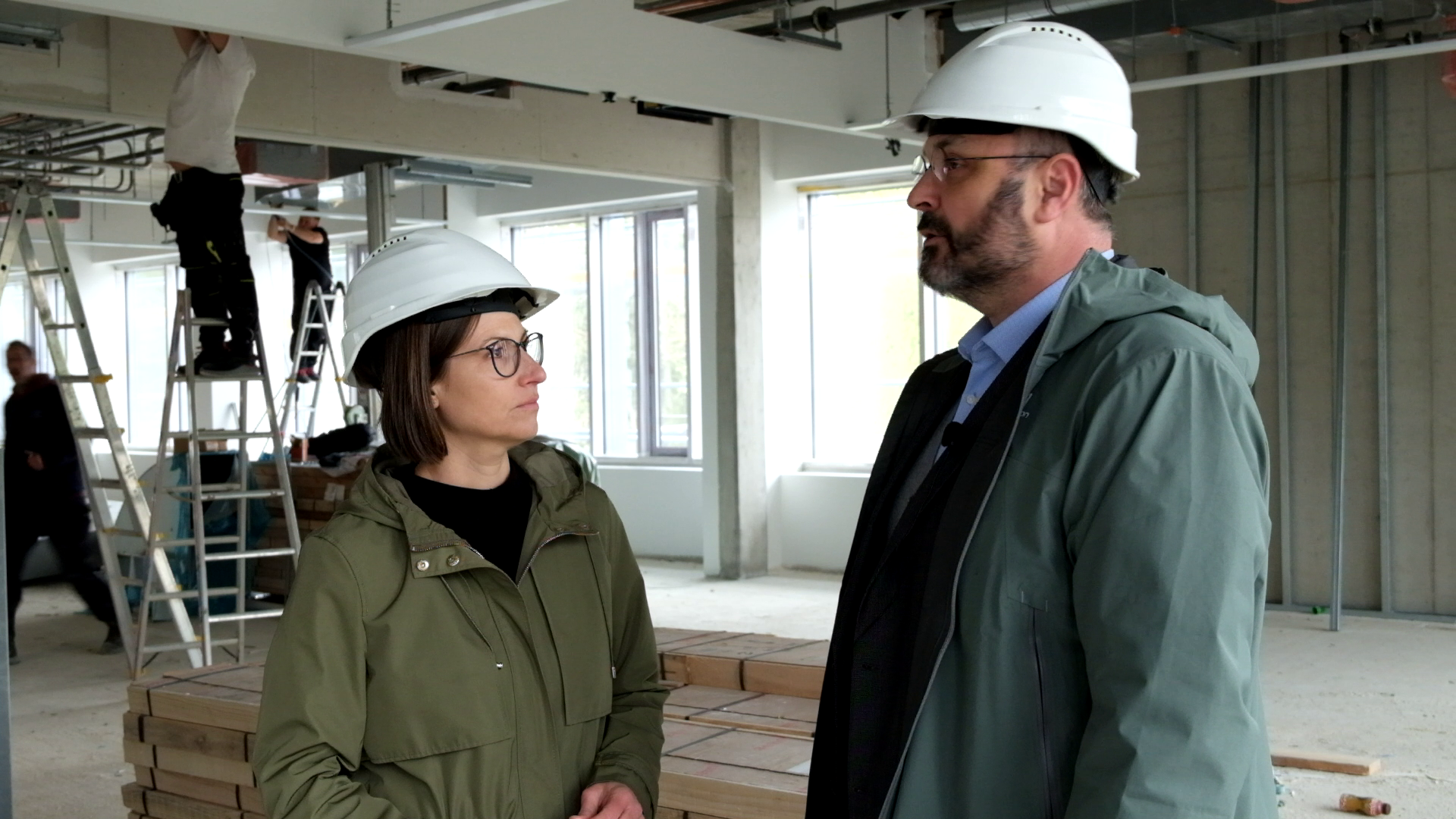 Zwei Personen mit Bauhelm im Gespräch auf einer Baustelle