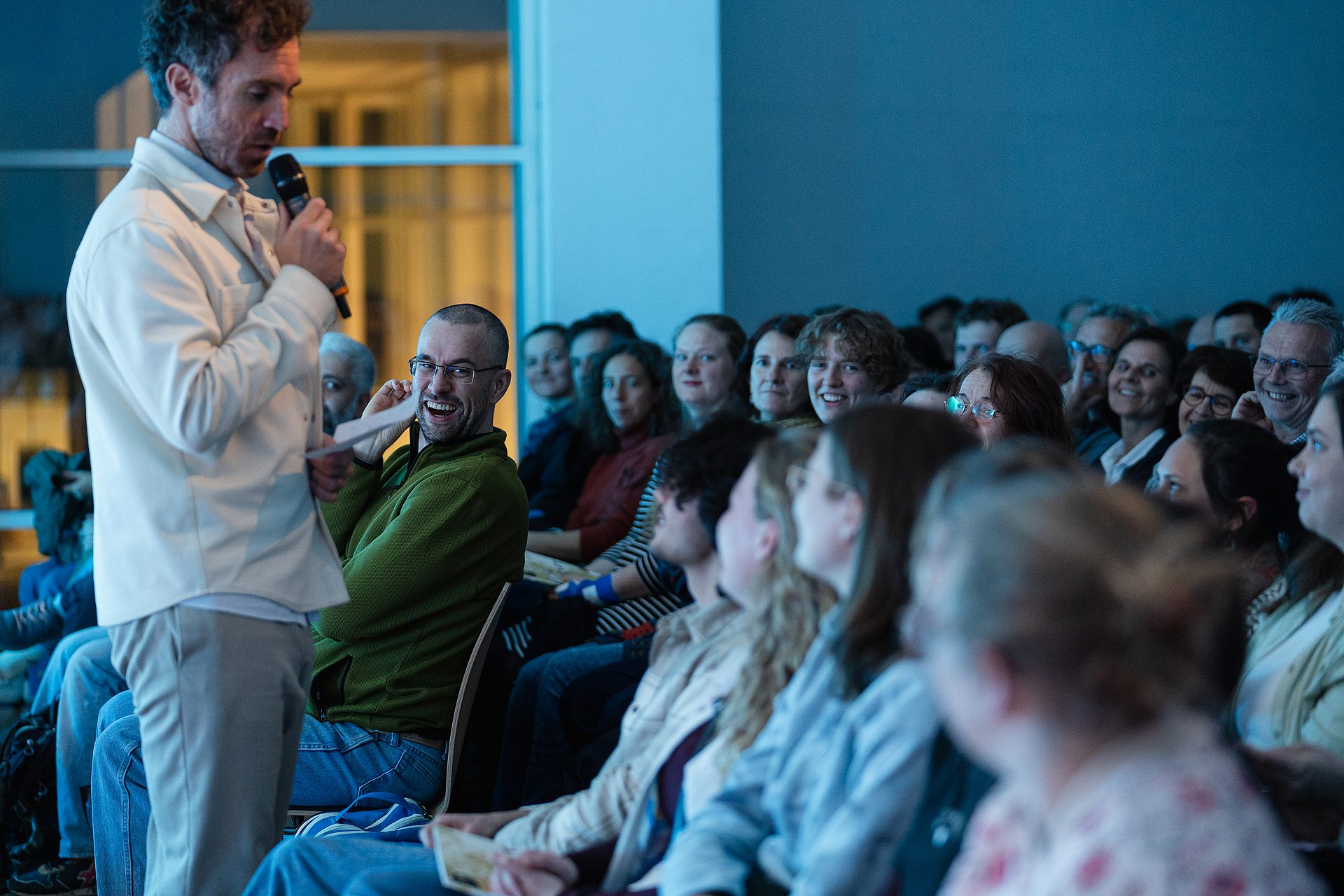 Bild von Moderator Julian Heun und Teil des Publikums beim Poetry Slam