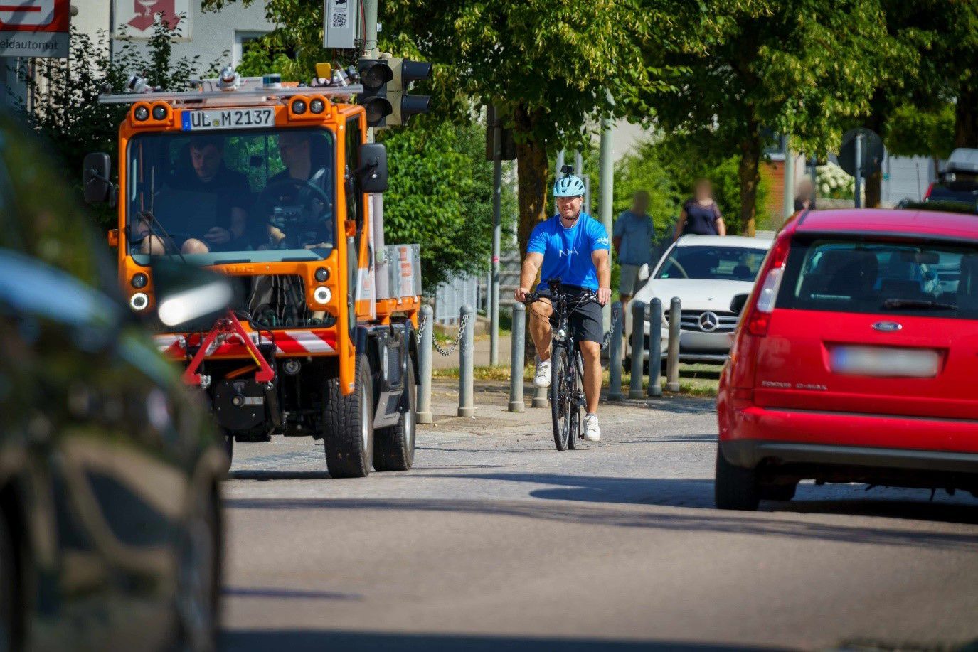 Straßenszene mit Kehrmaschine und Radler