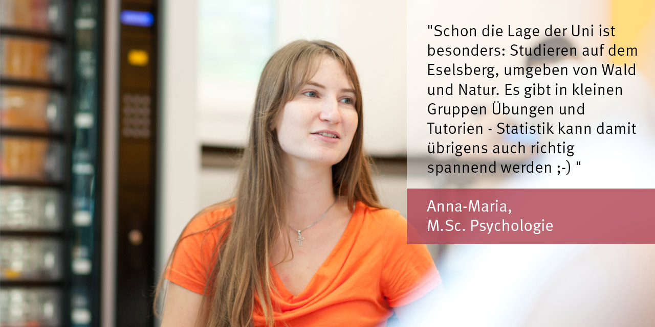 Eine Studentin mit langen blonden Haaren und orangenem T-Shirt im Hintergrund ein Getränkeautomat. Man sieht nur den Oberkörper. 