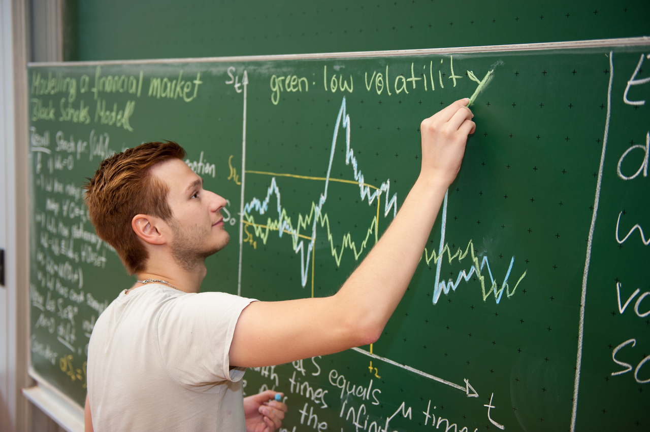 männlicher Studierender im Profil an Tafel mit mathematischen Formeln