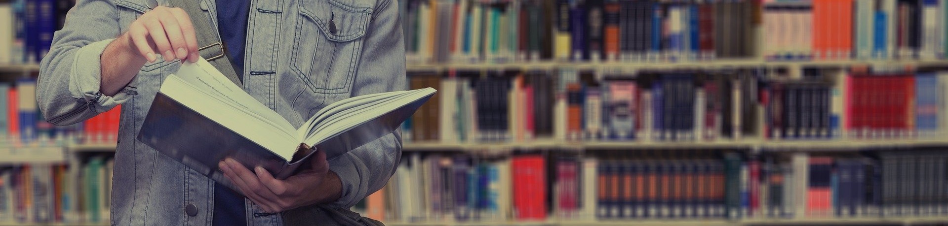 Studierender mit Buch in Bibliothek