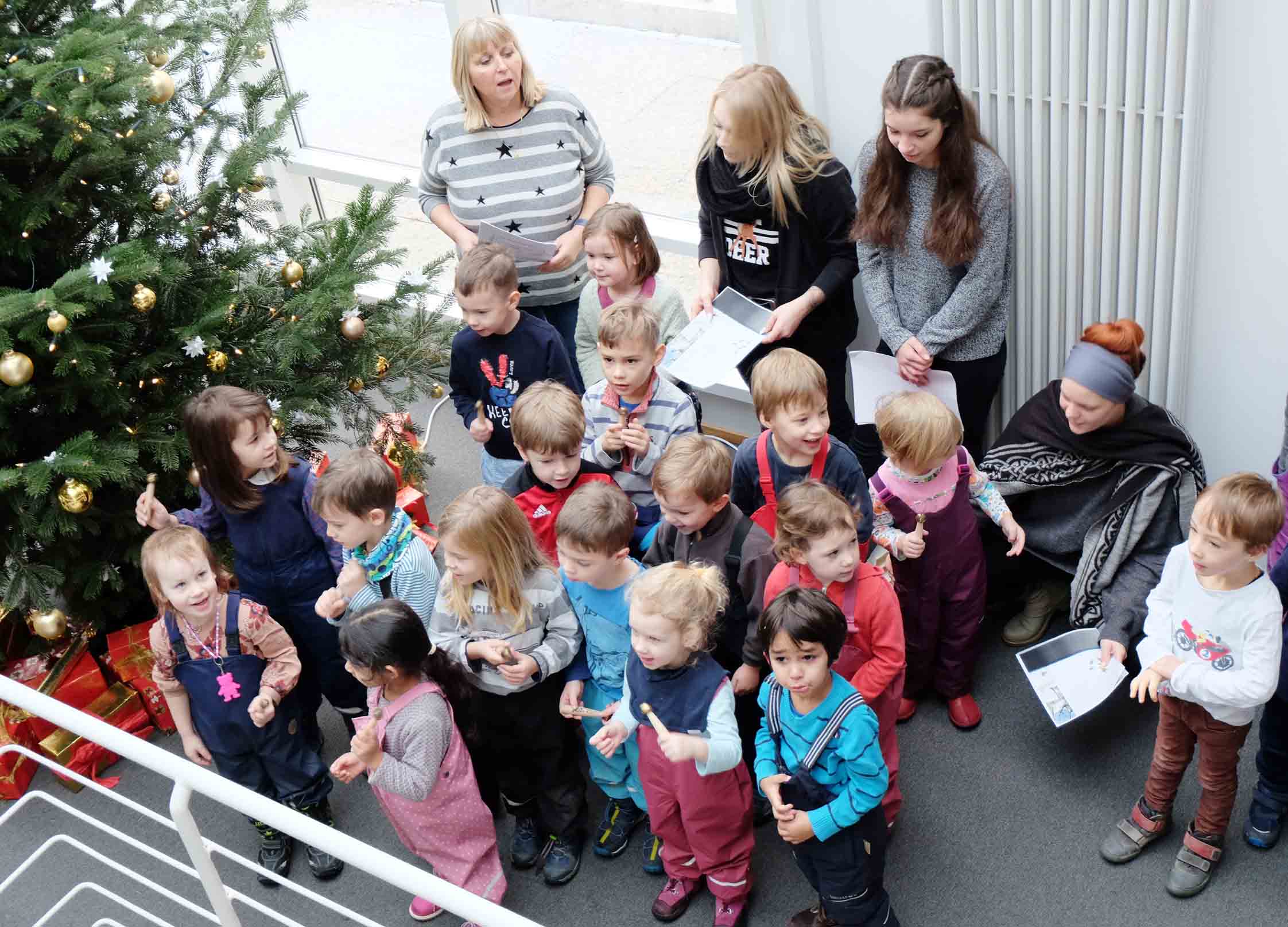 Kindergartenkinder vor dem Weihnachtsbaum