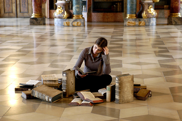 Student sitting on the floor in front of different books