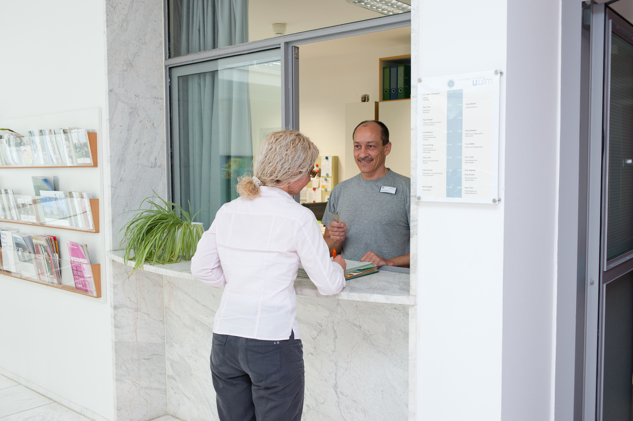 Hausmeister im Büro mit einer Beschäftigten im Gespräch